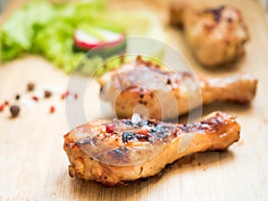 Grilled chicken drumsticks on a wooden Board with fresh vegetables Selective focus