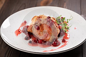 Grilled chicken fillet with cranberry sauce on white plate, close-up.