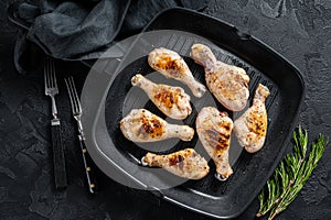 Grilled Chicken leg drumstick with herbs, poultry meat. Black background. Top view