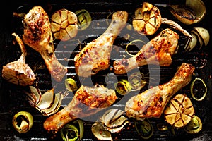 Grilled chicken legs with aromatic herbs and vegetables on a barbecue plate