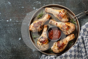 Grilled chicken legs with tomato sauce on  ceramic plate