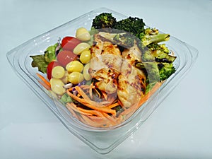 Grilled chicken placed on a salad in a clear bowl