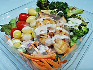 Grilled chicken placed on a salad in a clear bowl