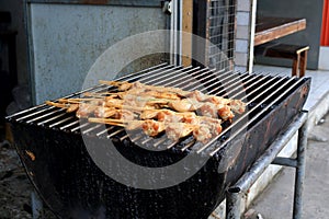 Grilled chicken\'s wing in bamboo camped on metal grate.