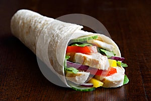 Grilled chicken and salad tortilla wrap isolated on dark background. No sauce.