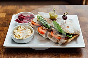 Grilled chicken sandwich made with homemade bread, tomato and lettuce served with beetroot salad and coleslaw