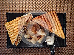 Grilled chicken sandwich with potato chips wafers and mayonnaise served on a black plate healthy breakfast brunch