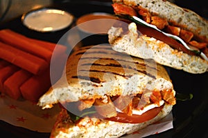 Grilled chicken sandwich with sliced carrots served on a plate