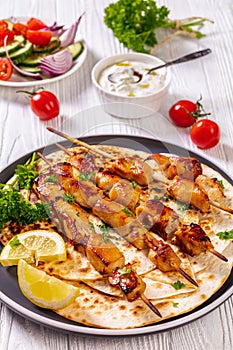 Grilled chicken skewers with flatbreads, top view