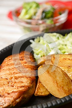Grilled Chicken Steak with fried potatoes in rural style and coleslaw salad served in a tray over white background.