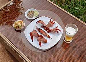 Grilled chicken on white plate with parsley, salad and beer outdoors