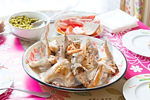 Grilled chicken wings on a dish, fresh tomatoes and canned green peas on a table