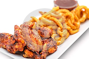 Grilled chicken wings with french fries an tomato sauce on white plate