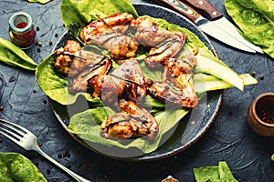 Grilled chicken wings on lettuce leaves
