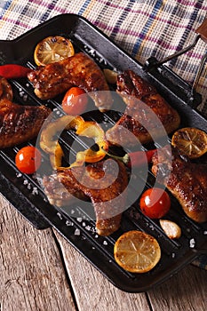 Grilled chicken wings with vegetables in a grill pan close-up.