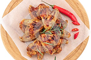 Grilled chicken wings on wooden cutting board isolated on white background