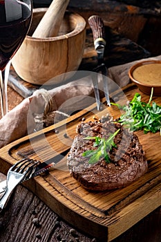 Grilled chuck beef steak with wine, knife and fork on a wooden Board. Whole roast piece of meat