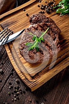 Grilled chuck beef steak with wine, knife and fork on a wooden Board. Whole roast piece of meat
