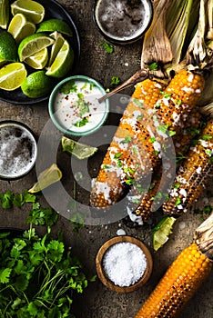 Grilled corn cobs with fresh herbs,lime,beer and salt, served on stone table