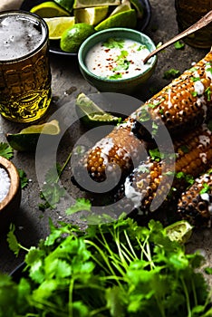 Grilled corn cobs with fresh herbs,lime,beer and salt, served on stone table
