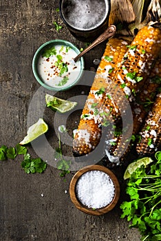 Grilled corn cobs with fresh herbs,lime,beer and salt, served on stone table