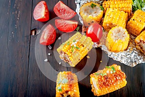 Grilled corn cobs with solt, spices and tomatoes