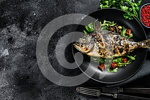 Grilled Dorado fish with arugula salad and tomatoes. Black background. top view. Copy space
