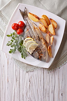 Grilled dorado fish with fried potatoes and tomato. Vertical top