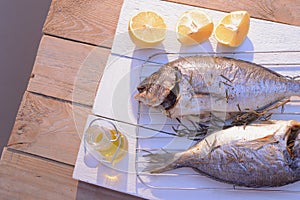 Grilled dorado fish on a grill grate with lemon and olive oil bottle