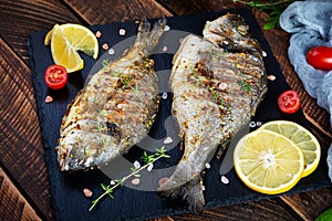 Grilled dorado fish on wooden background. Roasted seafish with spice and herbs