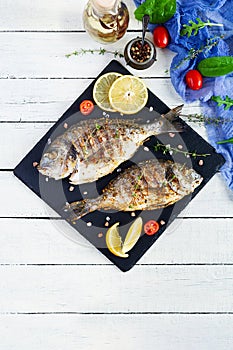 Grilled dorado fish on wooden background. Roasted seafish with spice and herbs