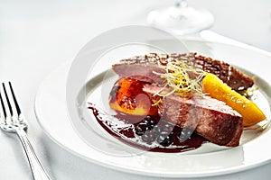 Grilled duck breast with peaches in berry sauce, grilled duck fillet on a white plate, close-up of duck meat with