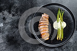 Grilled duck breast steak with baked asparagus. Black background. Top view. Copy space