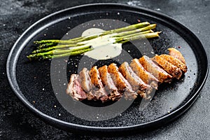 Grilled Duck fillet steaks with asparagus. Black background. Top view