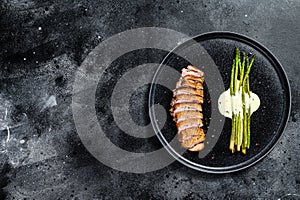 Grilled Duck fillet steaks with asparagus. Black background. Top view. Copy space