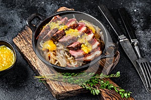 Grilled duck meat breast fillet steak with noodles and tangerines sauce. Black background. Top view