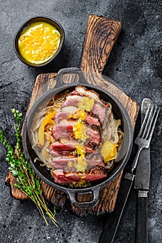 Grilled duck meat breast fillet steak with noodles and tangerines sauce. Black background. Top view