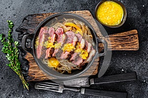Grilled duck meat breast fillet steak with noodles and tangerines sauce. Black background. Top view