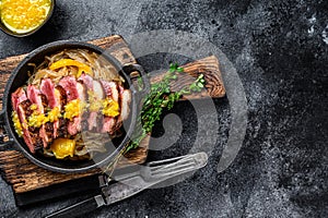 Grilled duck meat breast fillet steak with noodles and tangerines sauce. Black background. Top view. Copy space