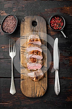 Grilled duck meat, on wooden serving board, on old dark  wooden table background, top view flat lay