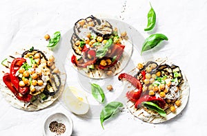 Grilled eggplant, sweet peppers, cauliflower and spicy chickpeas vegetarian tortillas on a light background, top view. Healthy foo