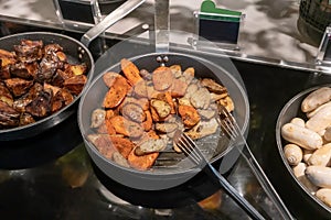 Grilled Eryngi mushroom and carrot in fry pan. Detail of buffet served in line