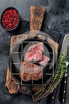 Grilled fillet mignon beef steak on a grill. Black background. Top view