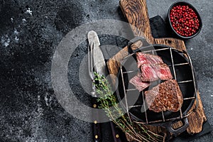 Grilled fillet mignon beef steak on a grill. Black background. Top view. Copy space