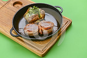 Grilled fillet mignon at the restaurant. Medallion steak dish with baked stuffed potato served in a frying pan