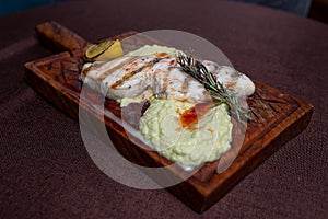 Grilled fish fillet with lemon and herb butter on a wooden board