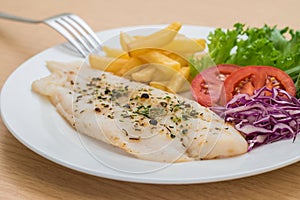 Grilled fish fillet steak with herb and french fries on plate