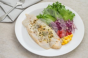 Grilled fish fillet steak with herb and vegetables on plate