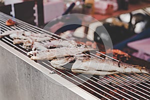 Grilled fish on the grill at street food market, selective focus