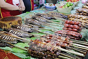 Grilled fish and meat skewers sold in an Asian food street market